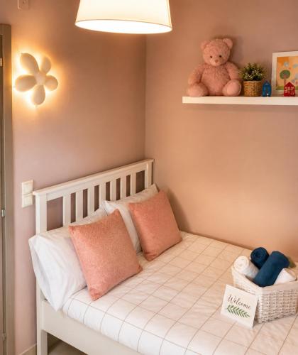 a small room with a crib with pillows and a teddy bear at Romantic loft in Tríkala
