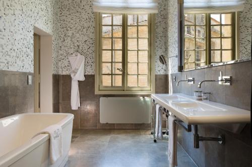 een badkamer met 2 wastafels en een bad bij La Maison d'Uzès Relais & Châteaux in Uzès