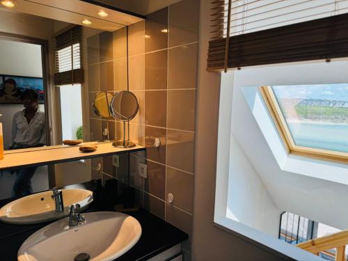 a bathroom with a sink and a mirror and a window at Appartement duplex vue mer in Audierne