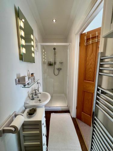 a white bathroom with a sink and a shower at Elmsleigh in Marhamchurch