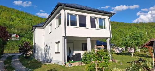 a white house with a hill in the background at Apartman Anna & Kamp Elza in Bihać