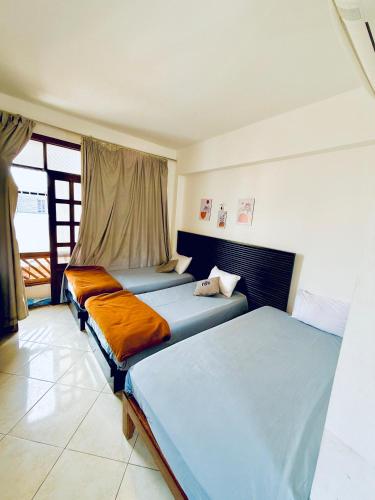 a bedroom with three beds and a window at Santa Maria Dahab Hotel in Dahab