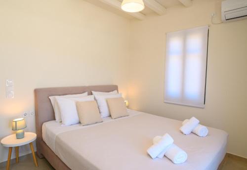 a bedroom with a large white bed with two pillows at "Araklos" Summer houses in Aegiali