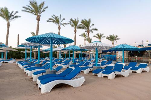 a bunch of blue and white chairs and umbrellas on a beach at MinaMark Beach Resort for Families and Couples Only in Hurghada