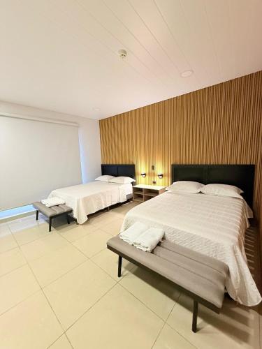 a bedroom with two beds and a bench in it at Apartamentos Marconela in San Mateo