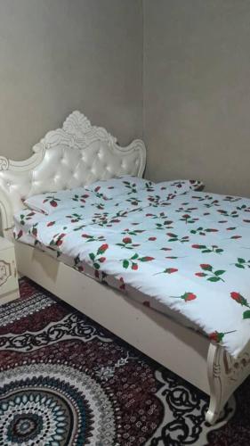 a white bed with flowers on it sitting on a rug at Gasthaus Jasur,Yakkakhona in Madovra