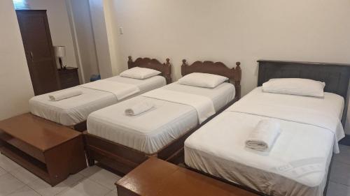 a room with three beds with white sheets at JM-RN Pensione House in Padre Burgos