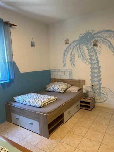 a bedroom with a bed with a palm tree mural on the wall at Apartments Lilly Weiss in Banjol