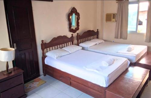 two twin beds in a room with a mirror at JM-RN Pensione House in Padre Burgos