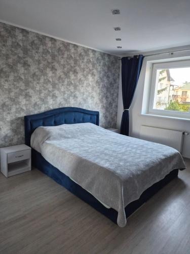 a bedroom with a blue bed and a window at Melnragė in Melnragė