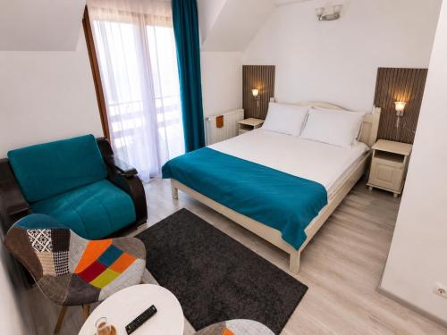 a bedroom with a bed and a chair and a table at Pensiunea Craiul Muntilor-Ranca in Ranca