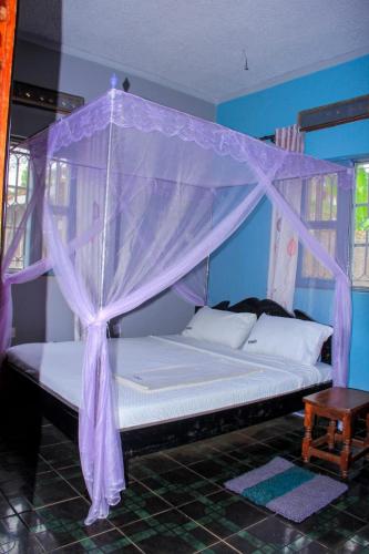 a bed with a canopy in a room at Tenzi BnB in Jinja