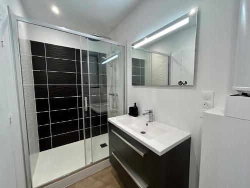 a white bathroom with a sink and a shower at Le 200 de la cale in Fouesnant