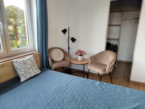 a bedroom with a blue bed and two chairs at Zakątek u Grzesia Gril & Chill in Trzebieszewo
