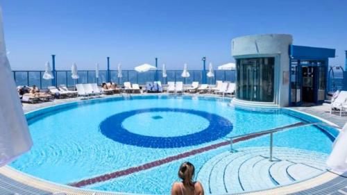 a woman sitting in front of a large swimming pool at Superb Beachfront Apartments with Shelter by Sea N' Rent in Tel Aviv