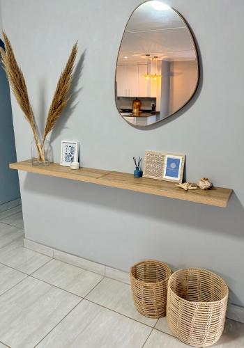 a mirror on a white wall with two baskets at Kingfish Cove, Pennington in Kelso
