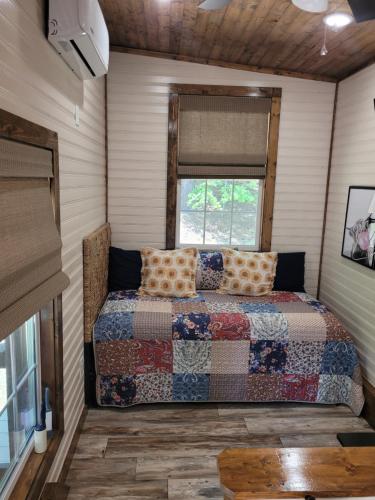 a bed in a small room with a window at The Tiny House at Deer Holler in Sugar Tree