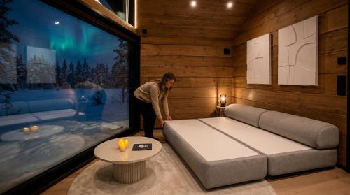 a woman in a room with a bed and a table at Levi Nordic Star Igloos in Levi