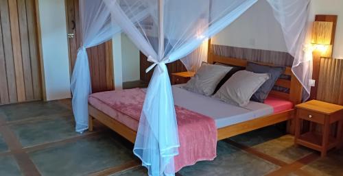 a bedroom with a bed with a mosquito net at Ecolodge Nosy Faly in Nosy Be