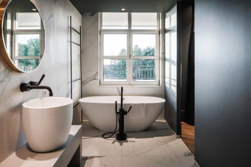 a bathroom with two sinks and a tub and a window at Van der Valk Hotel Apeldoorn in Apeldoorn