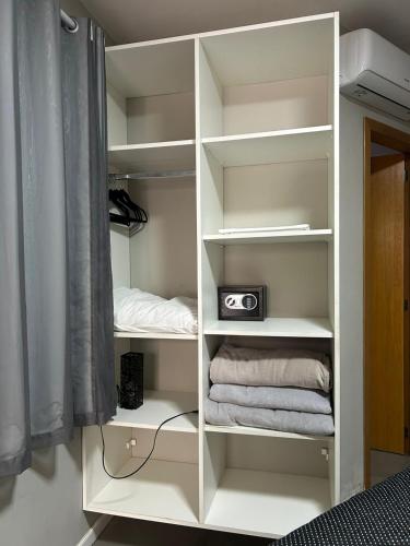 a white book shelf with a radio and towels at pousada das manas in Torres