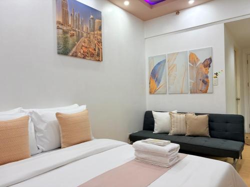 a bedroom with a white bed and a couch at Sunvida Tower Across SM Cebu CITY VIEW in Cebu City