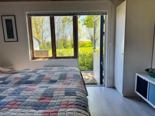 a bedroom with a bed and a large window at Gästhus i lummig trädgård - i idylliska Örum in Löderup