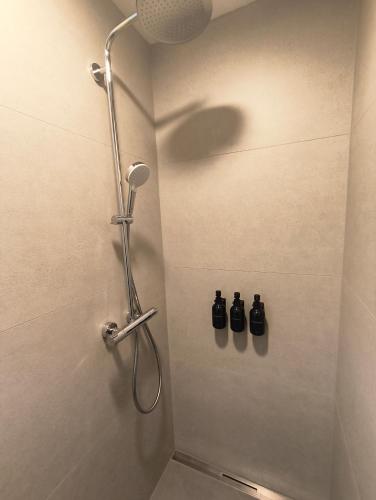 a shower in a bathroom with three bottles on the wall at Alpenblick Living in Stetten