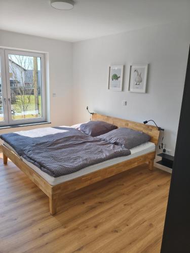 a bedroom with a wooden bed with a large window at Alpenblick Living in Stetten