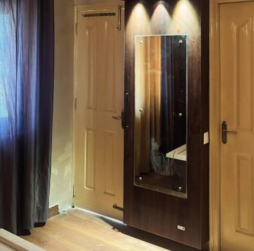 a wooden cabinet with a mirror next to a door at 22nd Weekend Stays in Bhīm Tāl