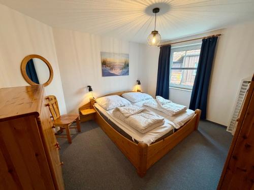 a bedroom with a bed and a mirror and a window at Ferienwohnungen Matschak OG rechts in Fehmarn