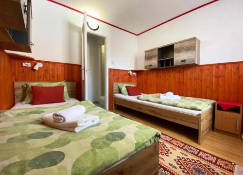 two beds in a room with wooden walls at Franc Llagami - Rooms in Vecsés