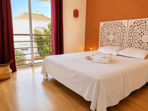 a bedroom with a white bed with a large window at Cabanas Terraces - Pool and seaview in Tavira