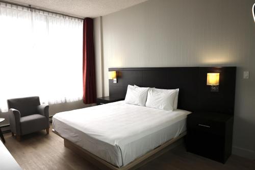 a bedroom with a bed and a chair and a window at Travelodge by Wyndham Quebec City Hotel & Convention Centre in Quebec City