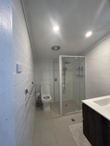 a bathroom with a shower and a toilet and a sink at Cowra Guest House in Cowra