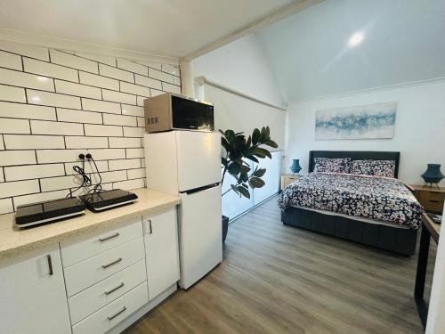 a bedroom with a bed and a white refrigerator at Cowra Guest House in Cowra