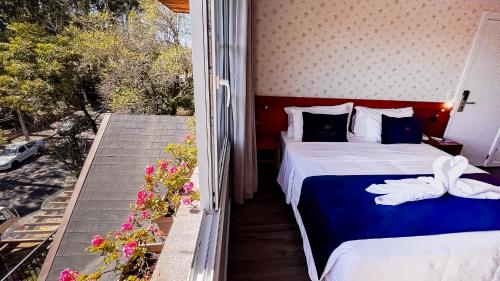 a bedroom with two beds and a balcony with flowers at Lapônia Hotel Gramado in Gramado