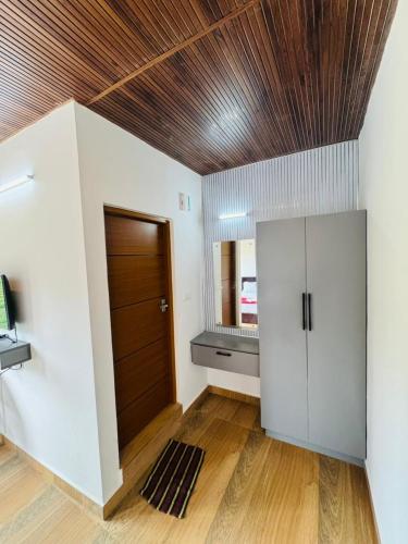 a living room with a wooden ceiling and a door at Pine Trees Home Holidays in Vagamon