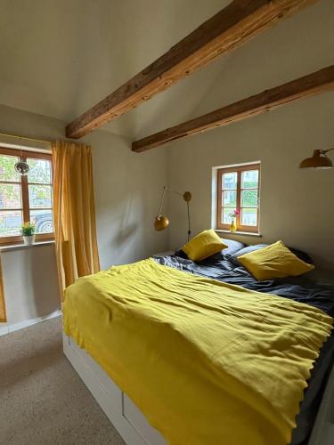 a bedroom with a bed with yellow sheets and windows at Fachwerk Anno 1789 in Lemgo