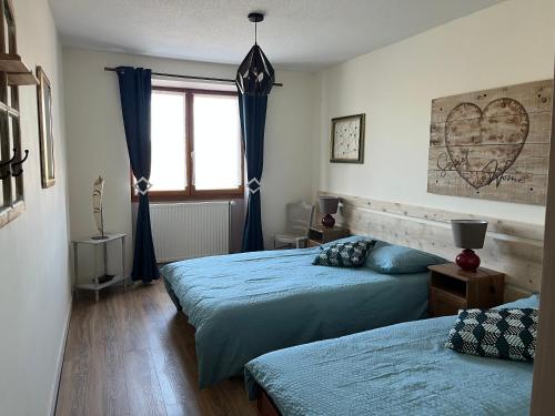 a bedroom with two beds and a heart picture on the wall at La Grande Ferme in Arinthod