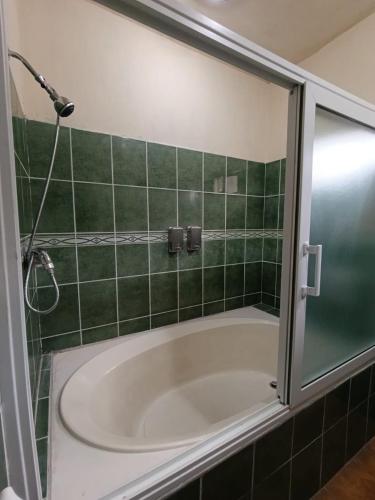 a bath tub in a green tiled bathroom at Hotel Premier in Escuintla