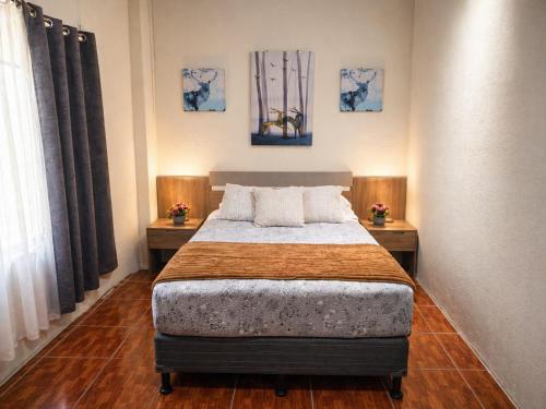 a bedroom with a bed with two tables and two windows at Hotel Premier in Escuintla