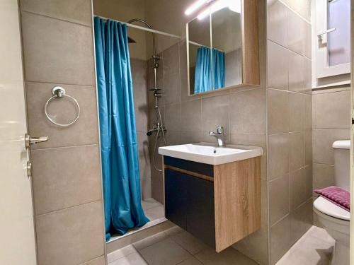 a bathroom with a sink and a shower with blue curtains at Delta Apartment • next to the beach in Roda