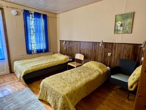 a hotel room with two beds and a chair at Majatalo Tyrni in Nakkila
