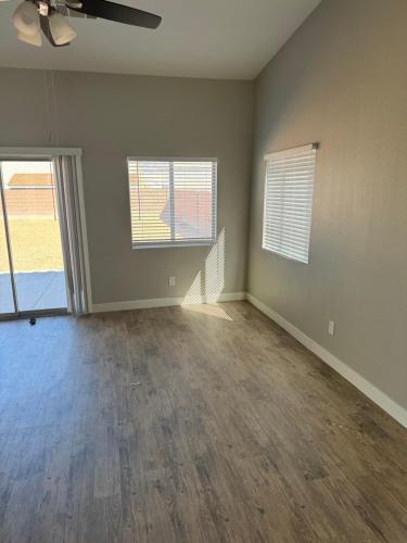 an empty living room with two windows and a ceiling fan at EdCccc life in Las Vegas