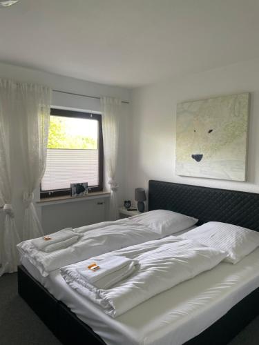 a bedroom with a bed with white sheets and a window at Emotion zentrumsnah für bis zu 6 Personen in Winterberg