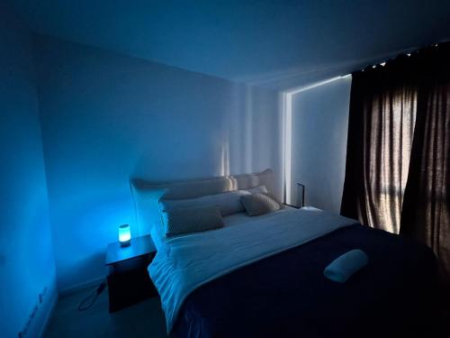 a blue bedroom with a bed and a blue light at Home Away From Home in Schönefeld