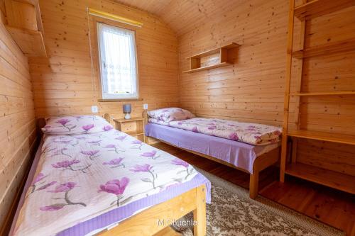 a bedroom with two beds in a wooden cabin at Domki pod Żukowcem in Solina