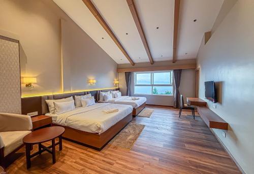 a hotel room with two beds and a tv at Hotel Old Bellevue Heritage Stay with Mountain Views in Chowrasta Darjeeling in Darjeeling