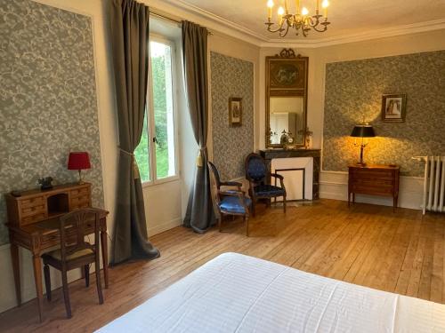 a bedroom with a bed and a desk and chairs at Château De La Coutancière in Brain-sur-Allonnes